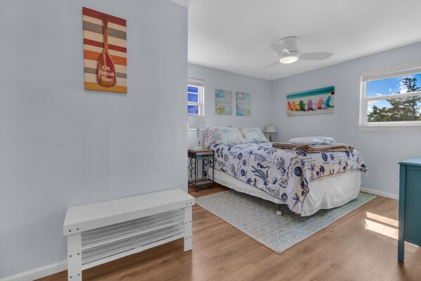 A bedroom with a bed, a nightstand, a desk, a window, and a ceiling fan. - Guest Favorite- walk to the beach! (Salvo)