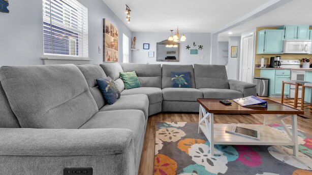A modern living room with a gray sectional sofa, a wooden coffee table, and a colorful rug. - Guest Favorite- walk to the beach! (Salvo)