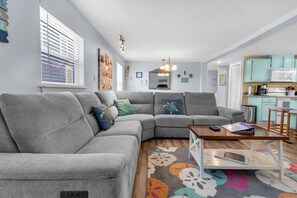 A modern living room with a gray sectional sofa, a wooden coffee table, and a colorful rug. - Guest Favorite- walk to the beach! (Salvo)