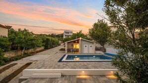 Ein modernes Haus mit Swimmingpool, kleinem Garten und einer Terrasse.