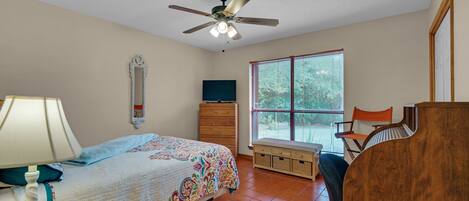 A bedroom with a bed, dresser, chair, and a ceiling fan.