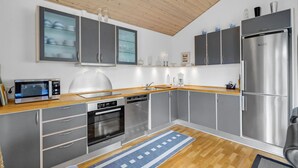 Una cocina moderna con gabinetes grises, un refrigerador de acero inoxidable, un microondas, un horno y un lavavajillas.