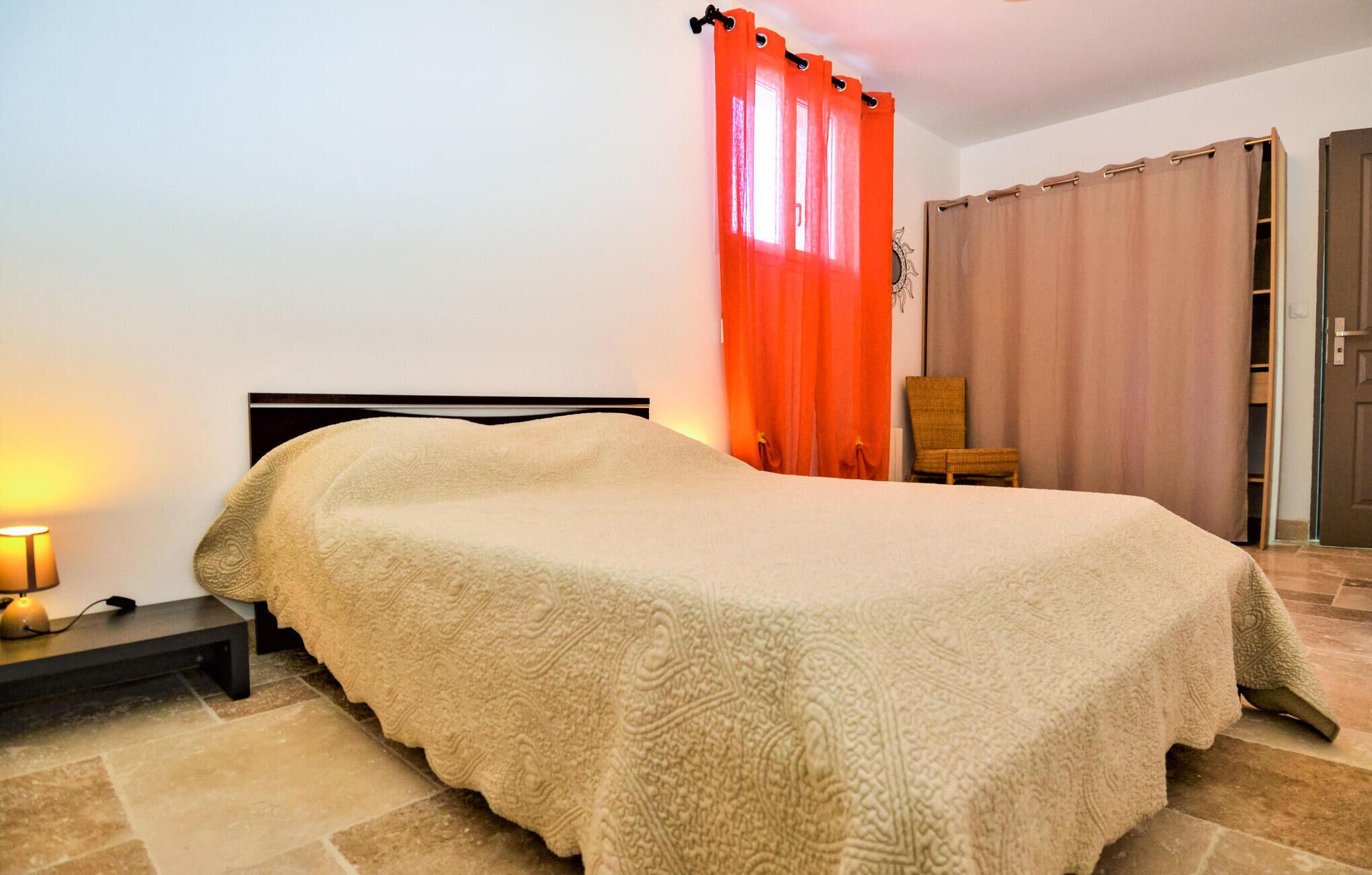 Een slaapkamer met een bed, een stoel, een nachtkastje en een kledingkast.
