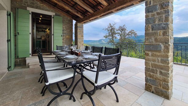 An outdoor patio with a stone table and chairs, a wooden ceiling, and a view of the countryside. - Villa with pool and air conditioning (Bartolići)