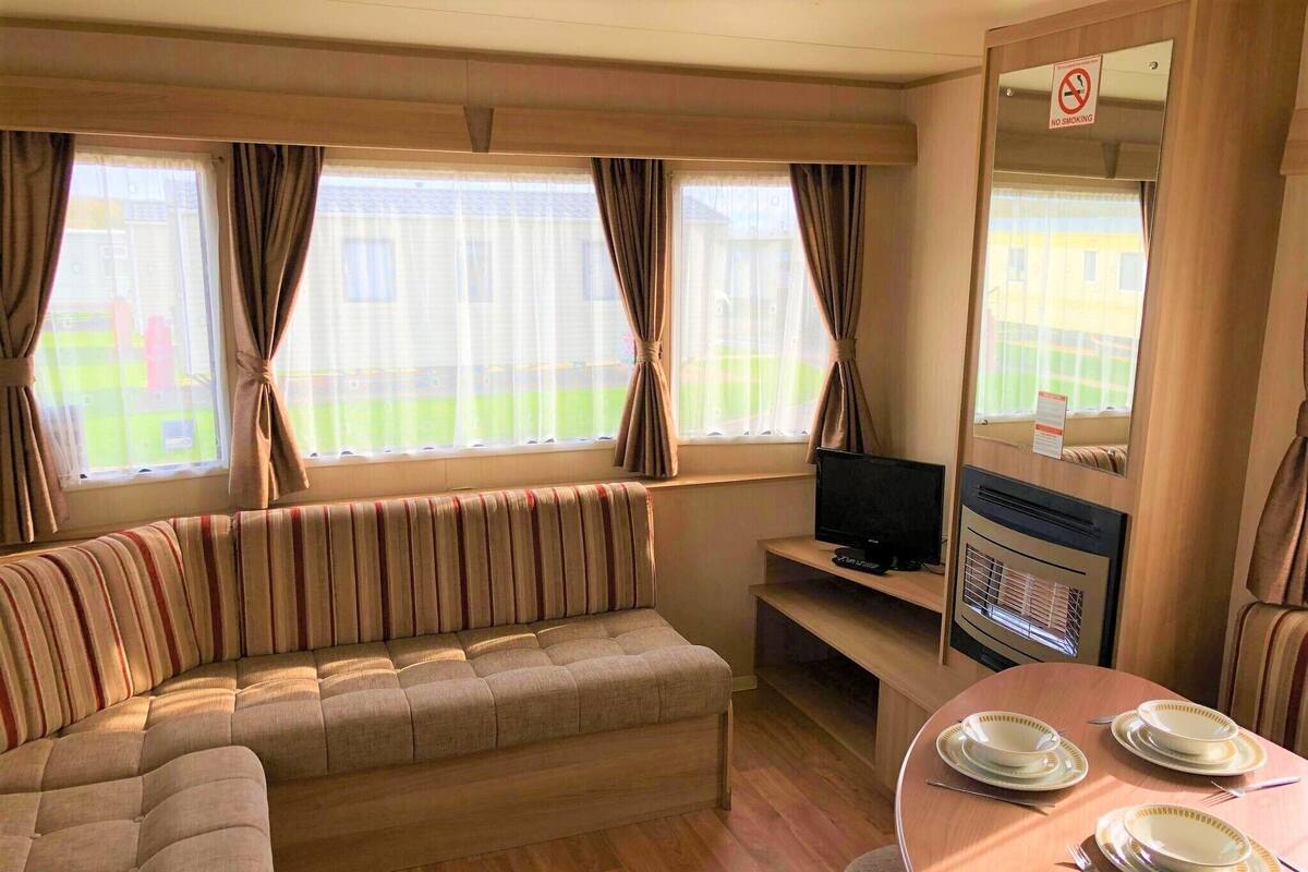 A cozy room with a sofa, a TV, a dining table with plates and cutlery, and a "No Smoking" sign.