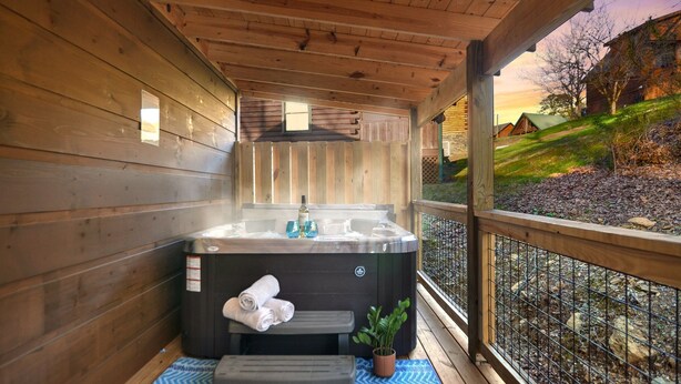 Una cabaña de madera con un jacuzzi, un banco y una maceta.