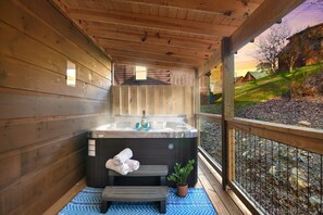 A wooden cabin with a hot tub, a bench, and a potted plant. - Cozy 3BDR Cabin Across From Convention Center | Fast WiFi | Hot Tub (Sevierville)
