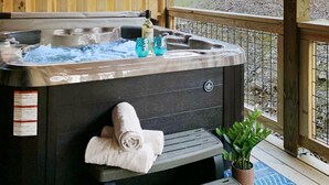 Un jacuzzi con cubierta de madera, una toalla y una botella de champú.