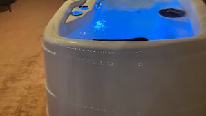 Un bain à remous avec un éclairage bleu, un dispositif de sauvetage fixé au mur et un tableau représentant une sirène.