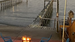 Une terrasse au bord de l’eau, dotée d’un foyer, de chaises et d’un mât pour drapeau.