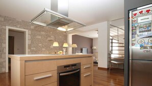 A modern kitchen with a built-in oven, a stainless steel refrigerator, and a stone backsplash. - Villa with air conditioning and pool (Pula)