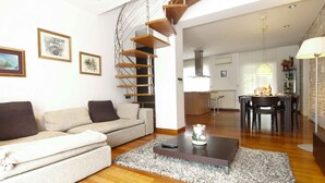 A modern living room with a spiral staircase, a sofa, a coffee table, and a dining area in the background. - Villa with air conditioning and pool (Pula)