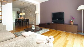 A modern living room with a staircase, a dining area, and a flat-screen TV on a wooden cabinet. - Villa with air conditioning and pool (Pula)