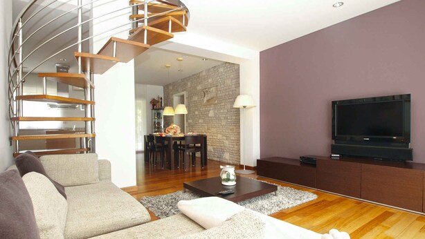 A modern living room with a spiral staircase, a dining area, and a flat-screen TV. - Villa with air conditioning and pool (Pula)