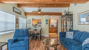 A spacious living room with a wooden ceiling, a dining area, and a kitchen in the background.