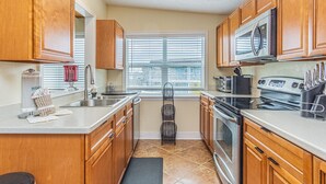 A kitchen with wooden cabinets, a stainless steel sink, a microwave, and a stove.