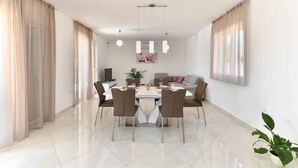 A modern dining area with a round table, four chairs, and a chandelier. - Villa with swimming pool and table tennis (Divšići)