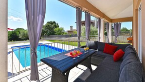 A balcony with a pool, a sofa, and a table with drinks. - Villa with swimming pool and table tennis (Divšići)
