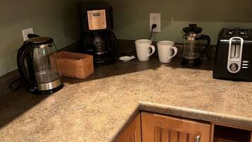 Een keuken met houten kastjes, een koffiezetapparaat, een broodrooster en een koffiemolen.