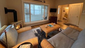 Ein gemütliches Wohnzimmer mit großem Fenster, Kamin und Fernseher.