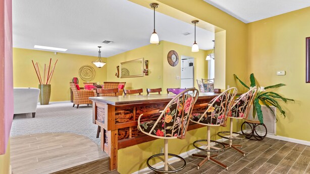 A kitchen with a bar area, wooden cabinets, and a large clock on the wall. - Behind Closes Doors just 4.5 miles away from the beach! (Vero Beach)