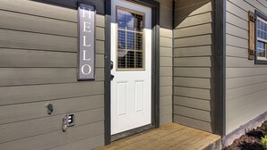 A house with a white door and a 'HELLO' sign on the wall.