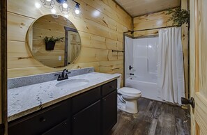 Ein Badezimmer mit Holzwänden, einem runden Spiegel, einem Waschbecken und einer Toilette.