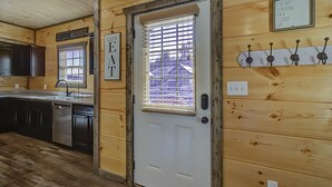 A wooden interior with a kitchen area, a door with a window, and a sign above the door.