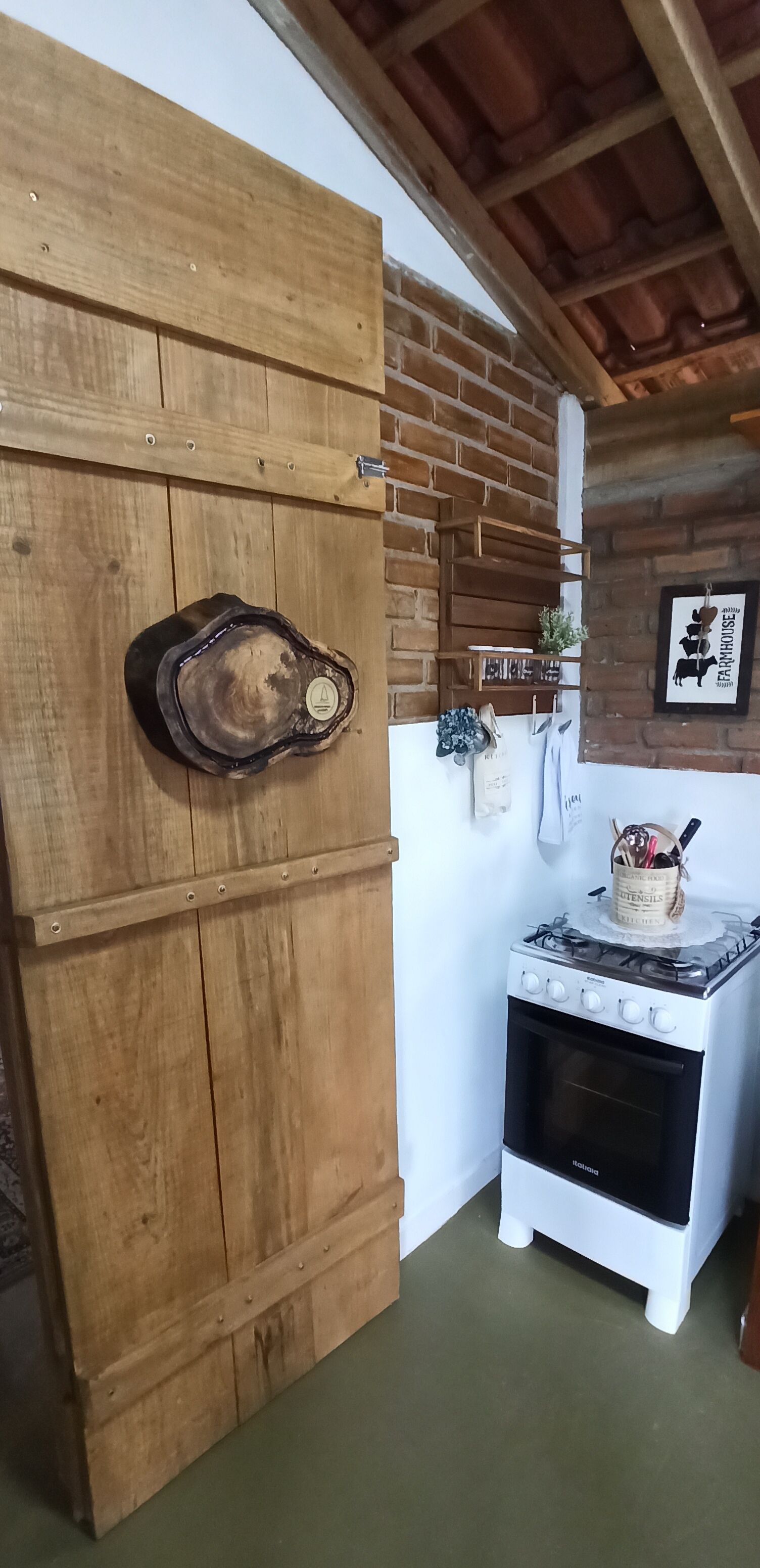 A rustic kitchen with wooden cabinets, a stove, and a brick wall.