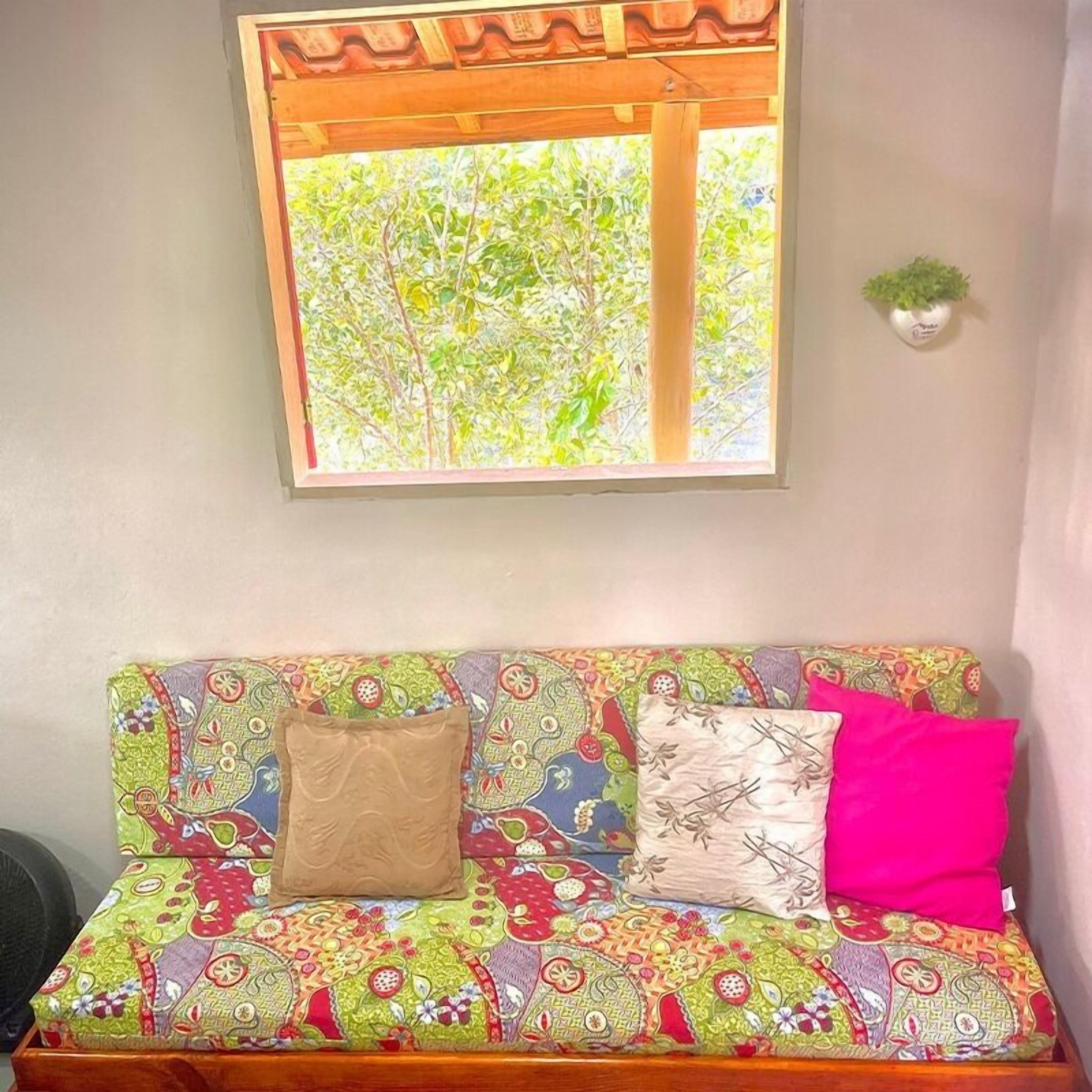 Un sofá con tapicería de estampado colorido, un cojín marrón y un cojín rosa.
