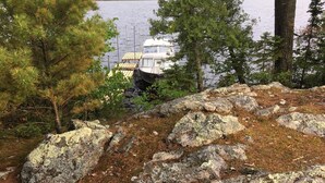 A lakeside cabin with a dock extending into the water, surrounded by trees and rocks.