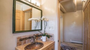 Un baño con tocador de madera, un espejo grande y una orquídea en maceta.