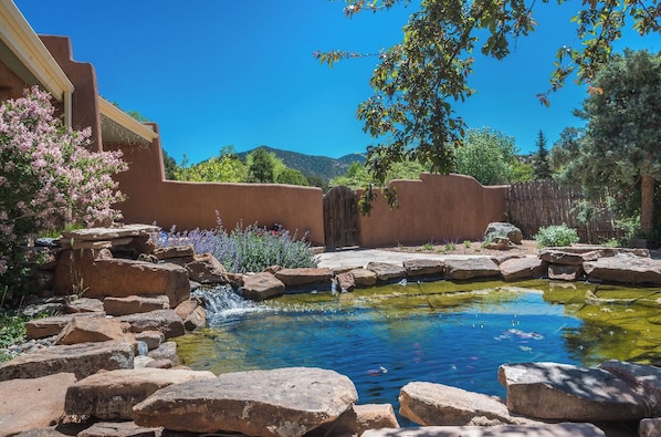 A garden with a pond, rocks, and a wooden fence.