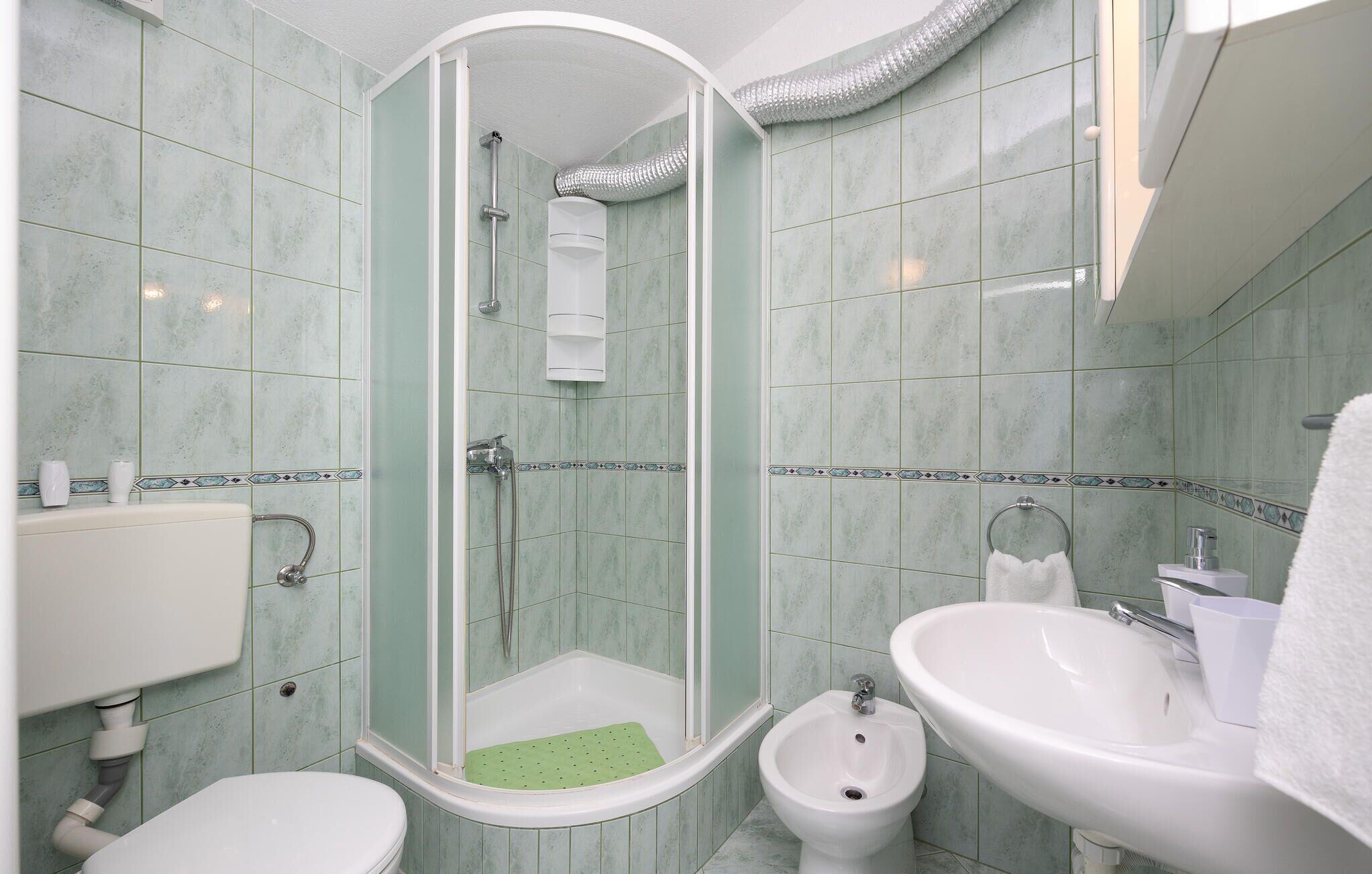 A bathroom with a glass-enclosed shower, a toilet, a bidet, and two sinks.