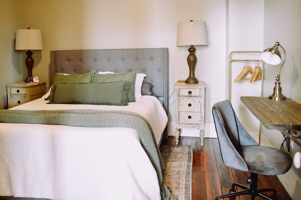 Une chambre à coucher bien rangée, avec un lit, des tables de chevet, un bureau et une chaise.