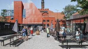 An outdoor seating area with tables and umbrellas in front of a building with a sign reading "MALTFABRIKKEN". - 2 bedroom beautiful home in Ebeltoft (Ebeltoft)
