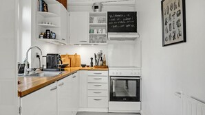 A modern kitchen with white cabinetry, a wooden countertop, a coffee machine, and a blackboard with text. - 2 bedroom beautiful home in Ebeltoft (Ebeltoft)