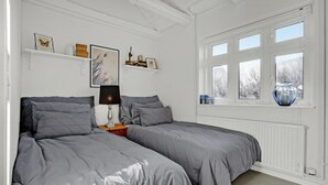 A bedroom with two beds, a nightstand, a lamp, wall art, and a window with a view. - 2 bedroom beautiful home in Ebeltoft (Ebeltoft)