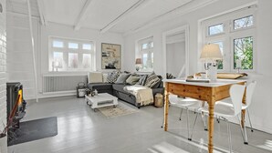 A spacious living room with a fireplace, a sofa, a coffee table, and a dining area with a table and chairs. - 2 bedroom beautiful home in Ebeltoft (Ebeltoft)