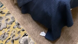 Yhden hengen sänky, jossa on harmaa ja sininen päiväpeite, valkoinen tyyny ja tummansininen peitto.