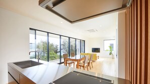 A modern kitchen with a large island, a dining area with chairs, and a view of the outdoors.
