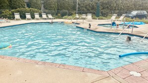 A swimming pool with lounge chairs and a covered area.