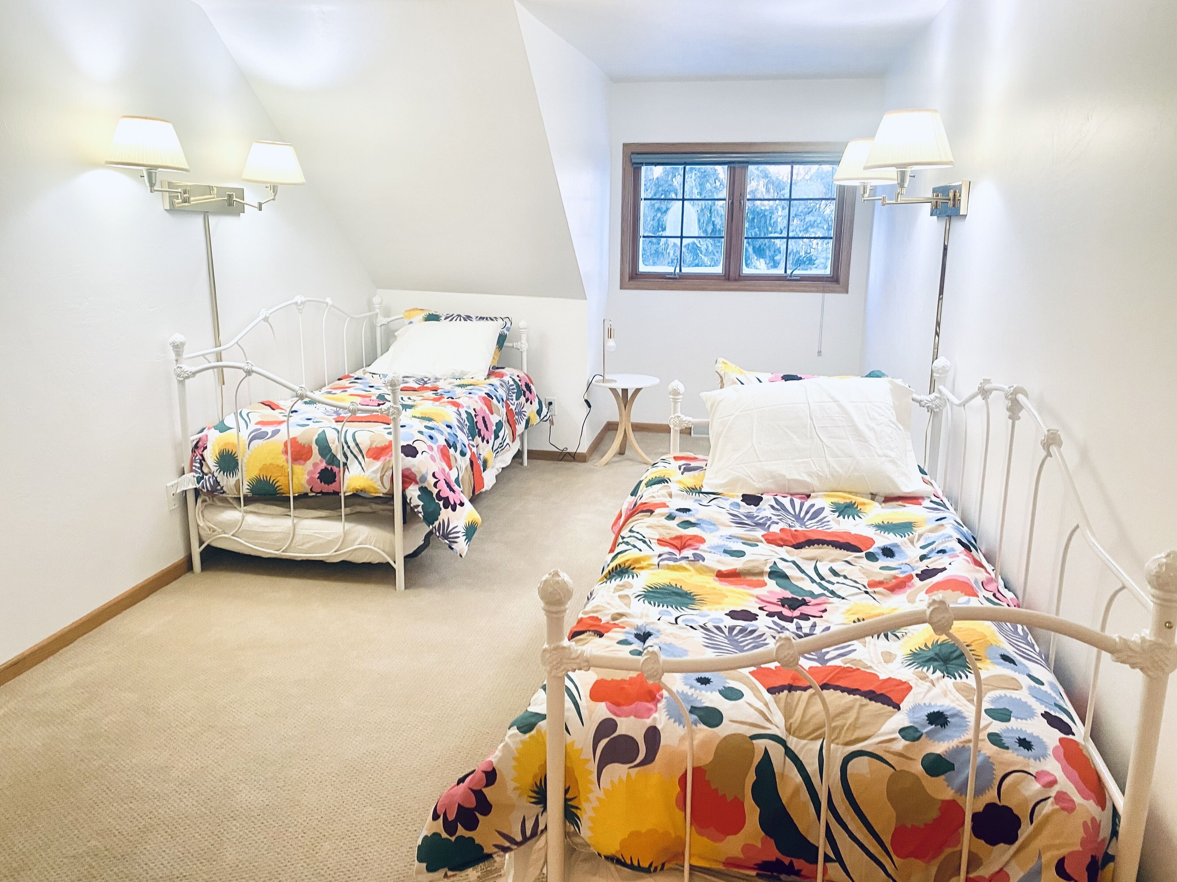 Une chambre avec deux lits simples, une petite table et une fenêtre.