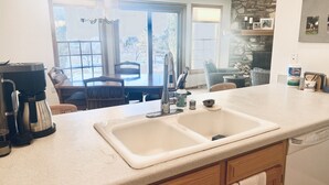 A kitchen with a double sink, a coffee maker, and a stone fireplace.