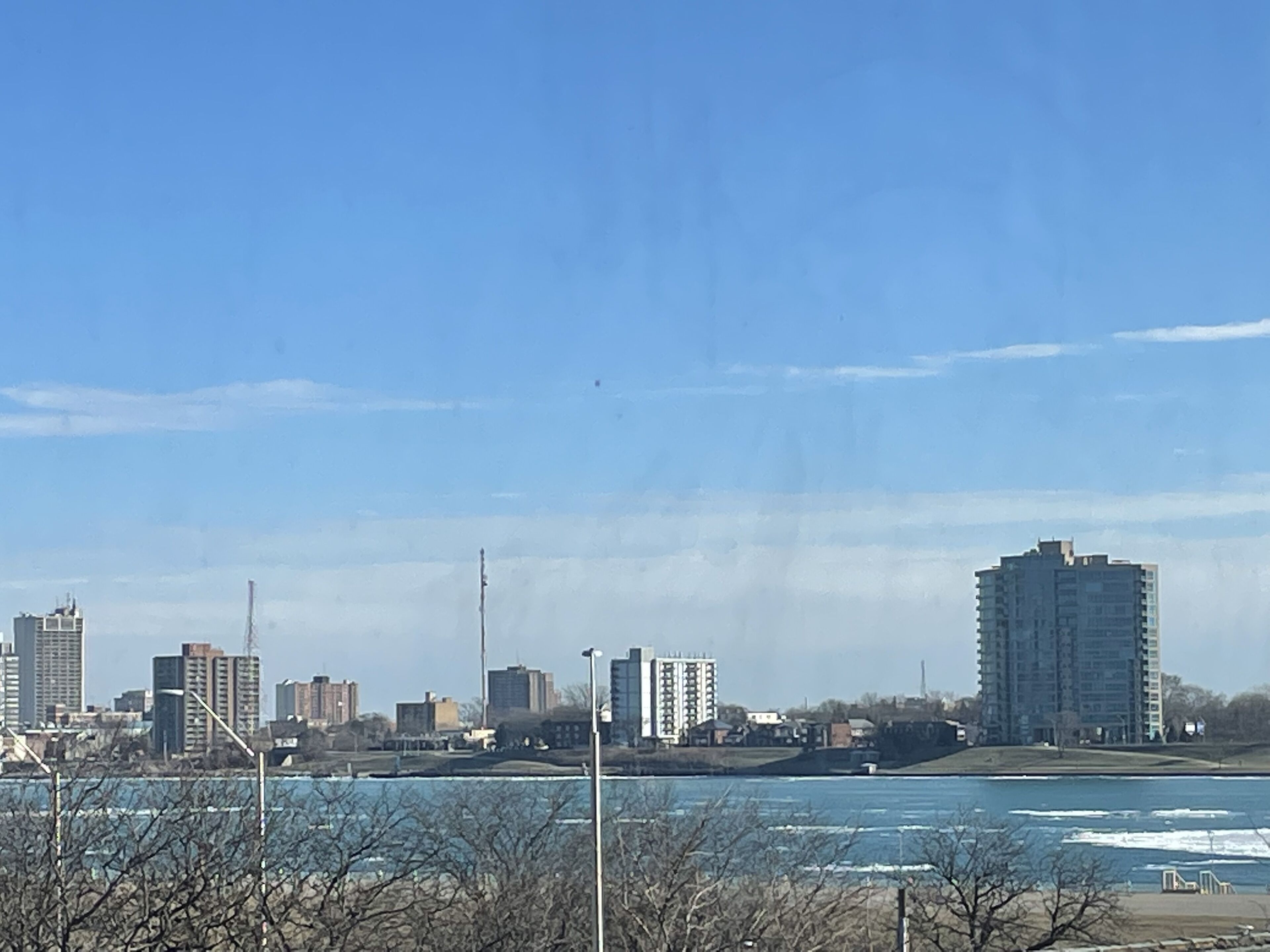 A city skyline with high-rise buildings, a river, and a clear sky.