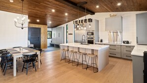 Une cuisine moderne dotée d’un îlot central, de tabourets de bar et d’un coin repas avec une table à carreaux.