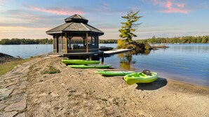 Un kiosque au bord d’un lac, avec des kayaks alignés sur la rive.