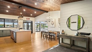 Une cuisine moderne avec un plancher en bois, un îlot central et un coin repas avec des chaises.