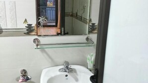 Un bagno con un lavandino bianco, una mensola in vetro sopra e uno specchio.