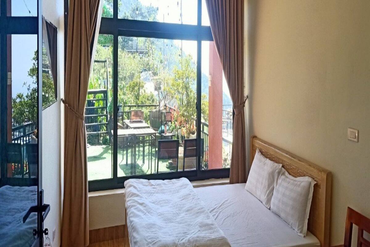 Un dormitorio con cama, cortinas, una ventana y vistas a un espacio exterior.